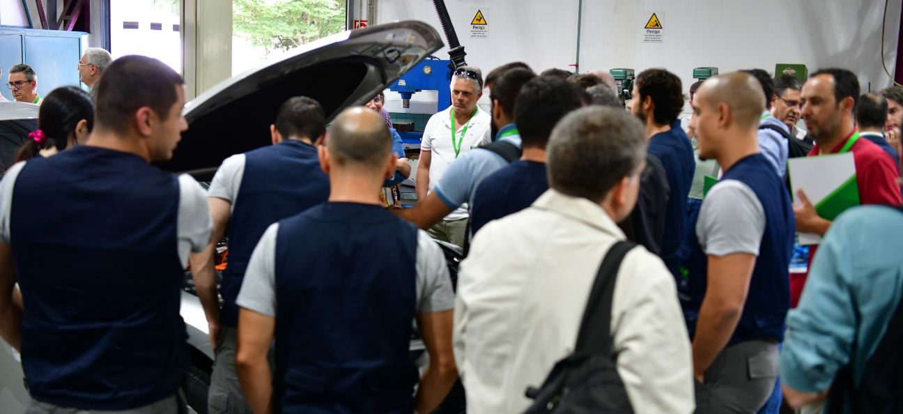 A imagem mostra várias formandos e alguns formadores a olhar para um automóvel com o capot aberto onde se mostra como é constituído atualmente um automóvel e com isso a evolução tecnológica no setor.